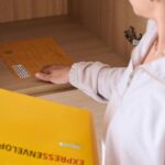 Close-up of a person storing an express envelope in a cabinet for secure delivery.