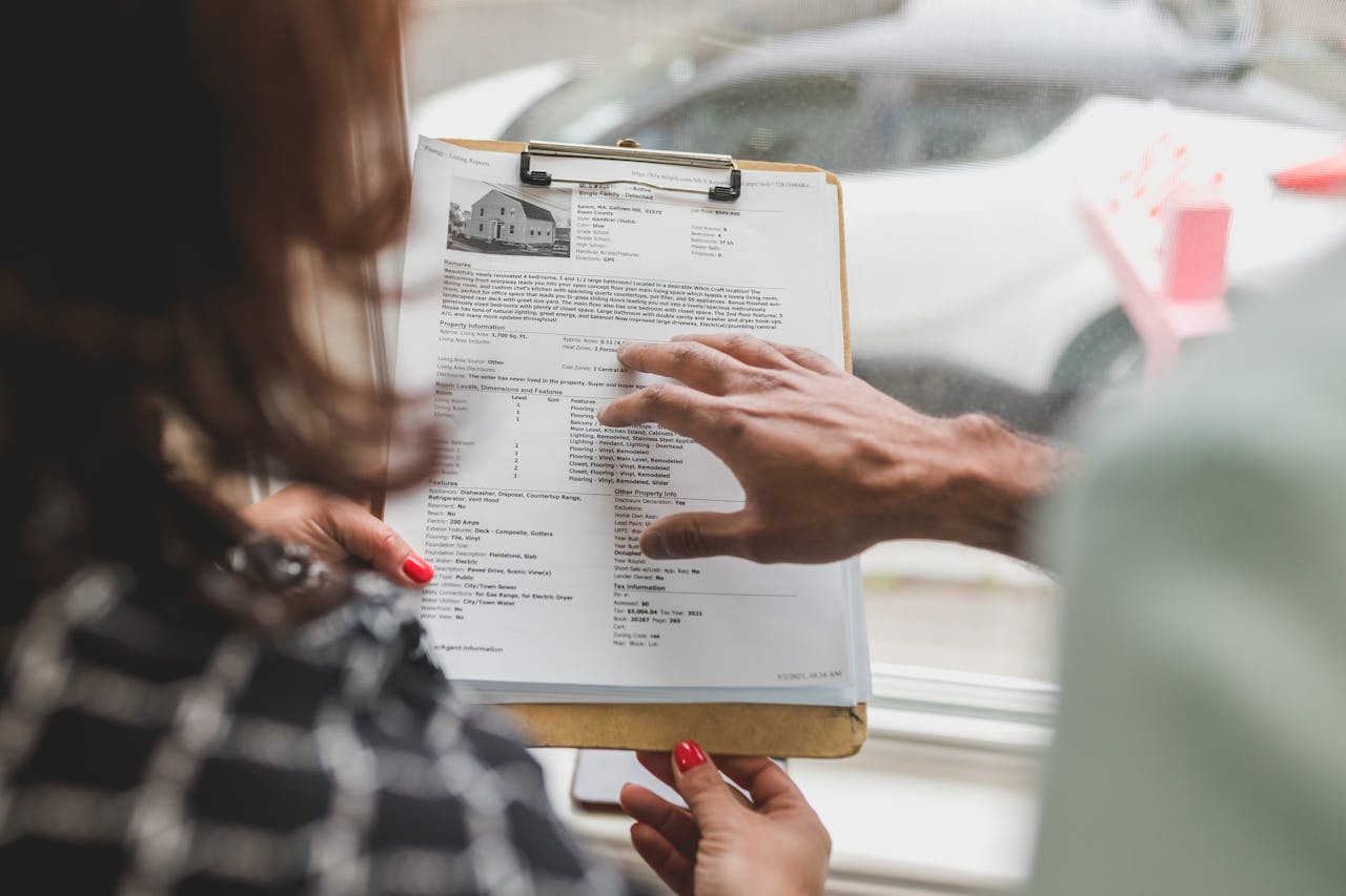 about-02 Real estate agent discussing property details with client using a clipboard indoors.
